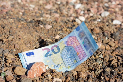 Twenty euro bill on soil ground with stone on top. Land investment, property money investor, bargain project, bet on life concepts