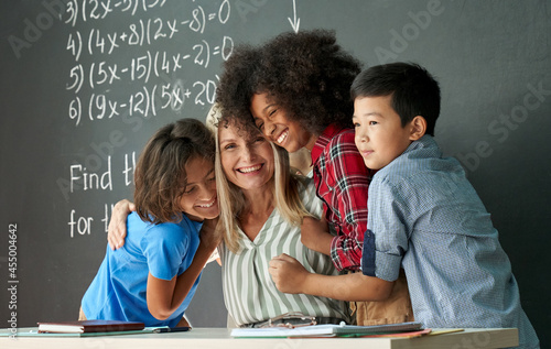 Wallpaper Mural Happy diverse kids, multicultural junior school children students hugging embracing female teacher appreciating and thanking educator in classroom, having fun, celebrating back to school concept