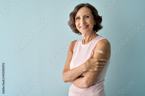Foto Smiling healthy mature older senior happy woman showing bandage on arm after getting vaccination