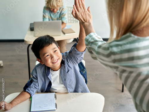 Tablou pe pânză Happy Asian kid boy giving high five to female teacher at class in classroom