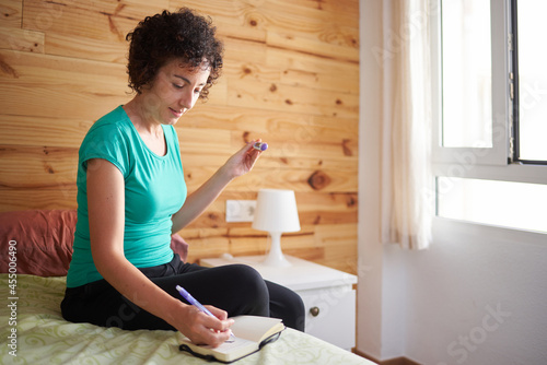 Foto A woman writes down in her notebook the temperature taken with her basal thermom