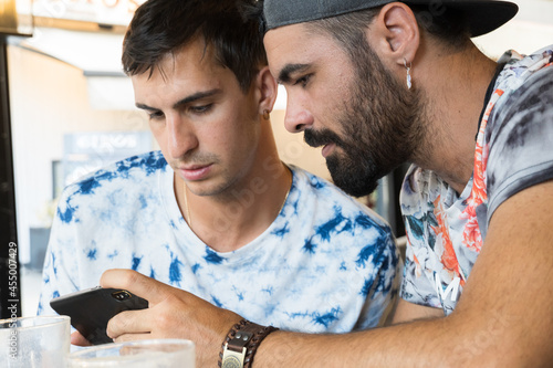Spanish friends with patterned shirt watching news on the phone