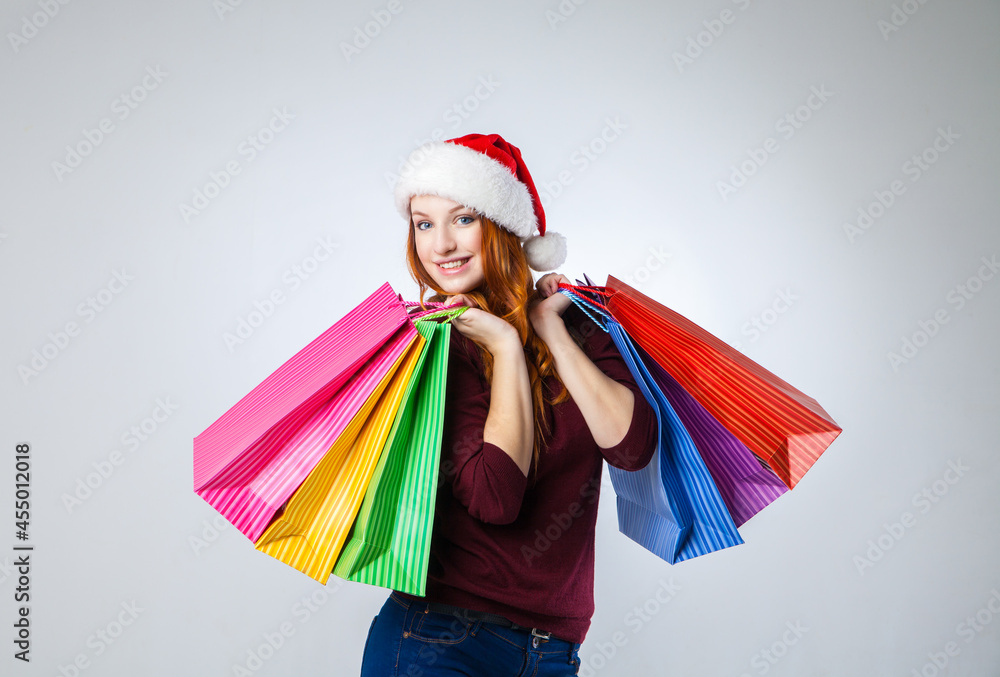 girl in winter hat with shopping bags over gray