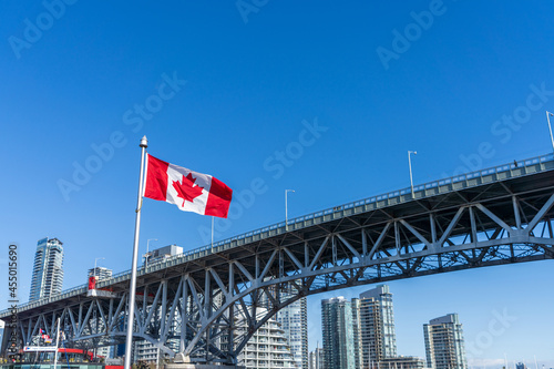 National Flags of Canada and Granville Bridge. Vancouver City skyscrapers skyline in the background. Concept of canadian urban city life. © Shawn.ccf