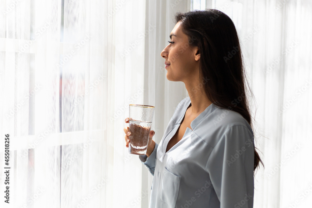 Adult caucasian woman drinks glass of pure water in the morning.