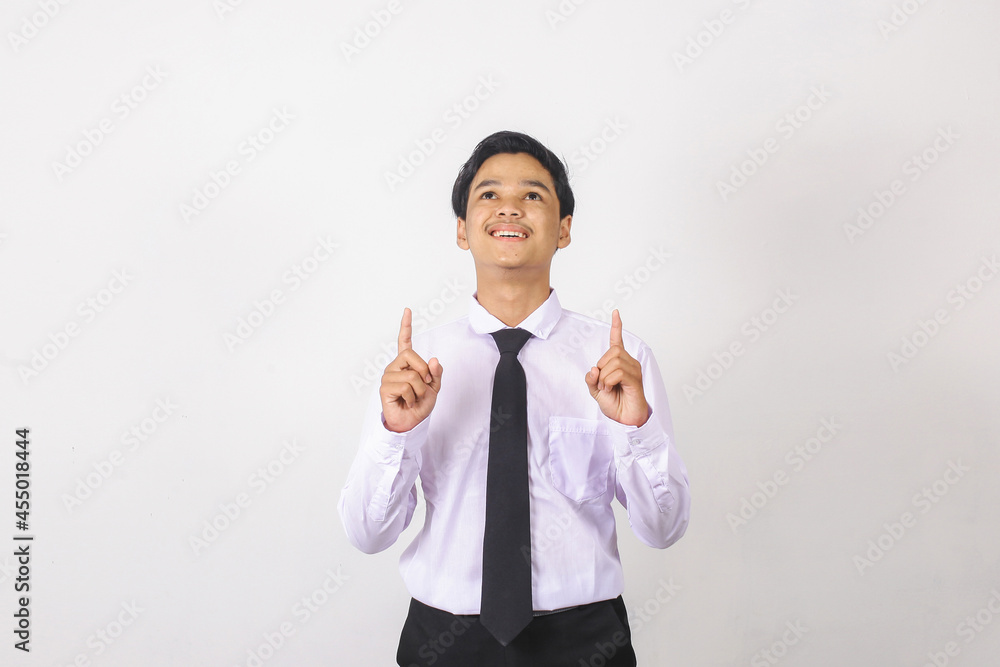 Smiling asian businessman in white shirt and black tie pointing up on empty space Smiling asian businessman in white shirt and black tie pointing up on empty space