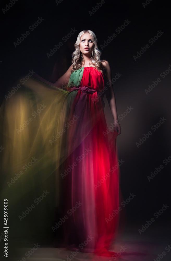 Young beautiful female model in colorful dress on black background