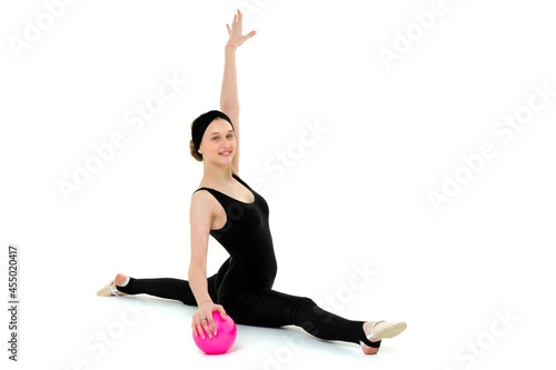 Flexible teenage girl doing gymnastic split with ball