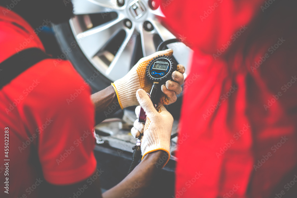 Closu up black mechanic inflating a tire in service station. checking ...