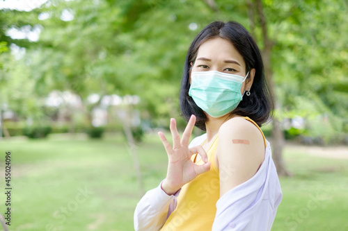 A pregnant mother wearing purple and yellow casual clothes shows plaster on her upper arm after receiving the vaccination.