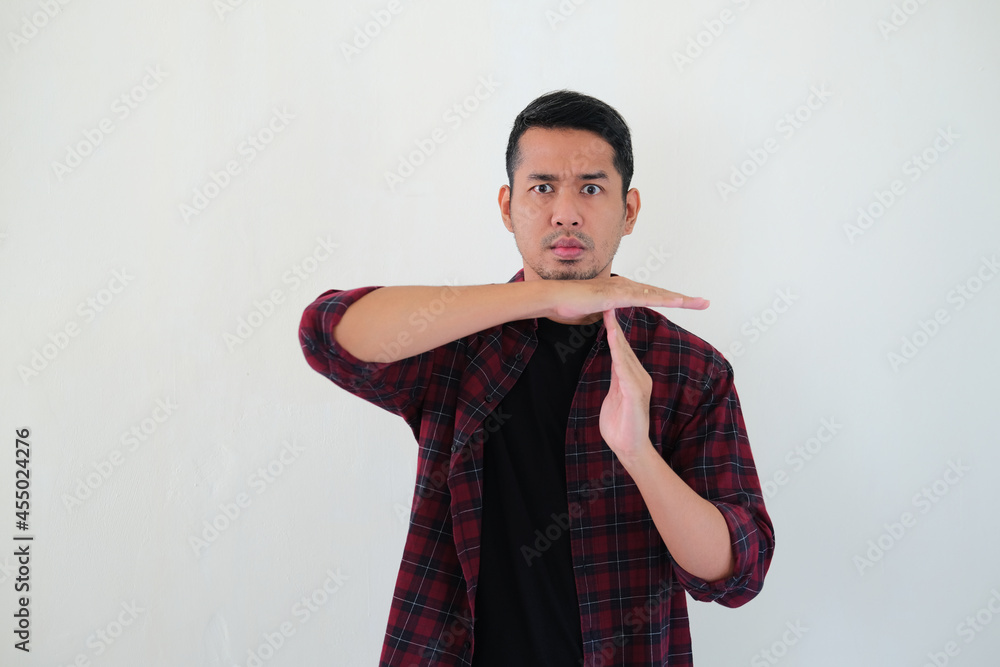 Adult Asian man giving timeout hand sign with serious face expression Adult Asian man giving timeout hand sign with serious face expression