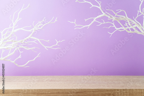 Empty wooden table over purple wall background with white branches. Halloween holiday mock up for design and product display.