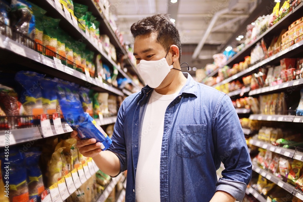 Asian man wearing surgical mask shopping in supermarket before lockdown.