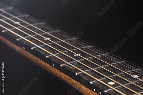 Close-up of strings on the fretboard of an acoustic guitar.