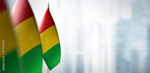 Small flags of Guinea on a blurry background of the city photo