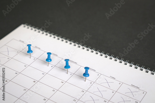 Blue pins on four days in a week on a calendar. Friday, Saturday and Sunday crossed out. Four day work week concept. photo