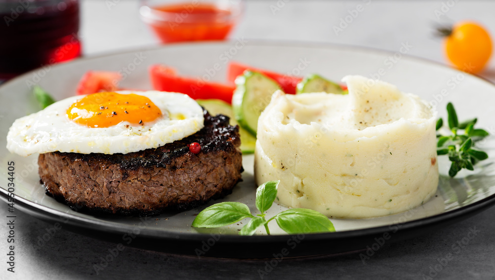Juicy Chopped steak with fried egg, mashed potatoes and tomato slices. Juicy Chopped steak with fried egg, mashed potatoes and tomato slices.