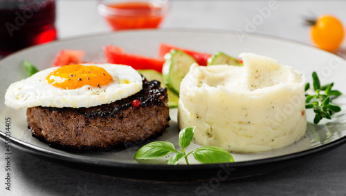 Juicy Chopped  steak with fried egg, mashed potatoes and tomato slices.