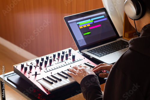 Fotografi asian amateur composer, arranger playing midi keyboard synthesizer for recording instrument track on computer