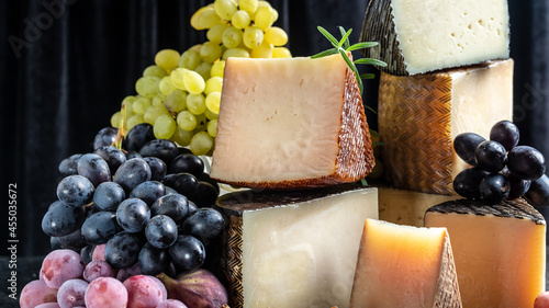 Assortment of different cheese types with grapes and figs. Cheese background. traditional pieces of Spanish, French, Italy cheese