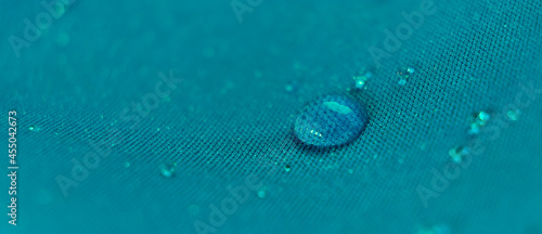 Water drops on the fabric. Rain Water droplets on blue fiber waterproof fabric. Water drops pattern over a waterproof cloth. Blue background.