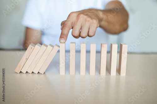 Solution concept with hand stopping wooden blocks from falling in the line of domino
