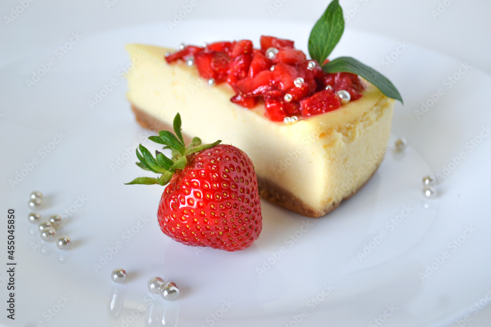 Piece of Cheesecake with Strawberries, Leaves and Silver Sprinkles on Plate Piece of Cheesecake with Strawberries, Leaves and Silver Sprinkles on Plate