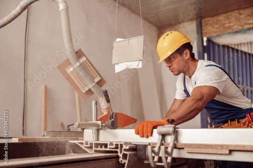 Serious male worker using woodworking equipment in workshop