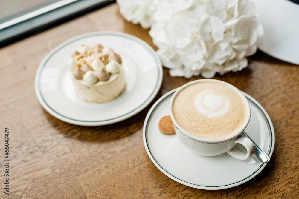 delicious dessert and a cup of coffee on the table. Enjoy a freshly baked dessert in a coffee shop, restaurant. A closeup shot of a little sweet decorative cake and a cappuccino. Soft selective focus. delicious dessert and a cup of coffee on the table. Enjoy a freshly baked dessert in a coffee shop, restaurant. A closeup shot of a little sweet decorative cake and a cappuccino. Soft selective focus.