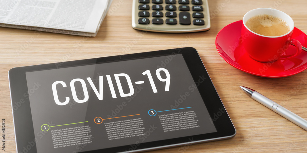 A tablet on a desk with the headline Covid-19