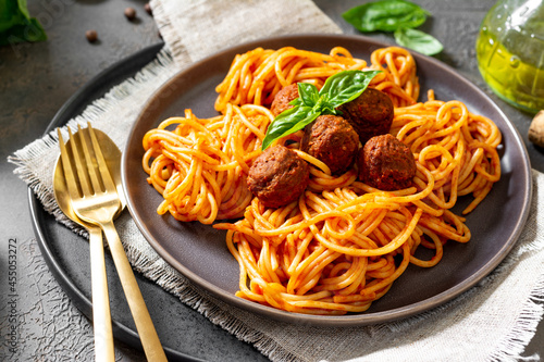 Spaghetti with meatballs in tomato sauce in a ceramic plate close-up. Traditional Italian pasta 