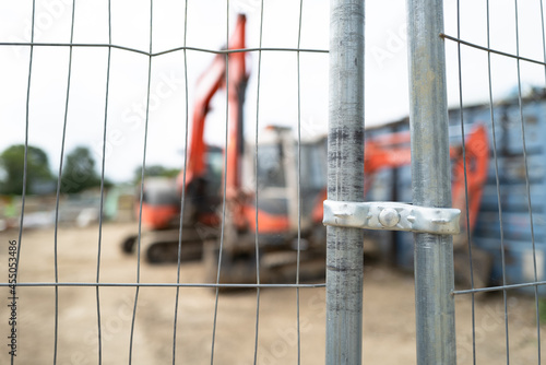 Heavy construction vehicles and equipment seen on a new housing development. Seen through steel safety fencing to prevent members of the public entering.