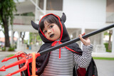 Asian child girl in demon costume holding black and red trident, Happy halloween concept