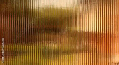 textured surface of brown polycarbonate with blurred reflections of objects, abstract background with raised lines and colored spots, flat texture of plastic street material