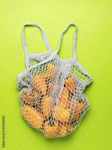 Fresh bell pepper in a mesh bag on a green background. Vegetarian food.