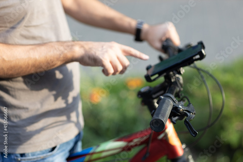 Man planning route pointing finger touch screen GPS navigation application in mobile phone on his bicycle bike
