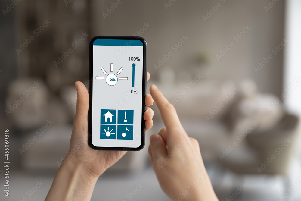 Close up young woman holding telephone with smart home app on screen, iot, virtual assistant, distant indoors temperature change or light regulation, remote climate control system, music control.