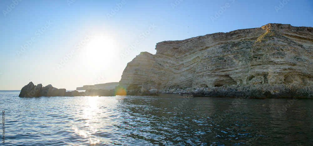 The sea shore with steep cliffs on a summer evening