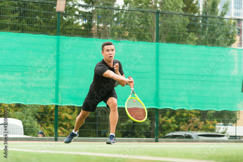 A male tennis player is elegantly hitting a tennis ball. A tennis player who looks like a dancer.