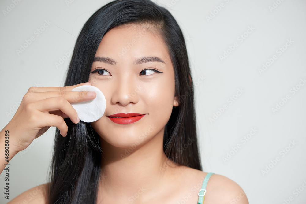 Happy woman caring about her fresh healthy skin of face with cotton pad - white background Happy woman caring about her fresh healthy skin of face with cotton pad - white background