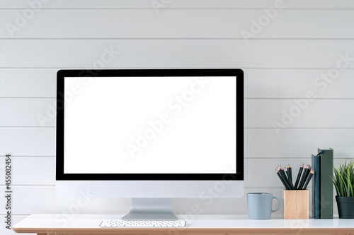 Blank screen desktop computer in minimal office room with decorations and copy space.