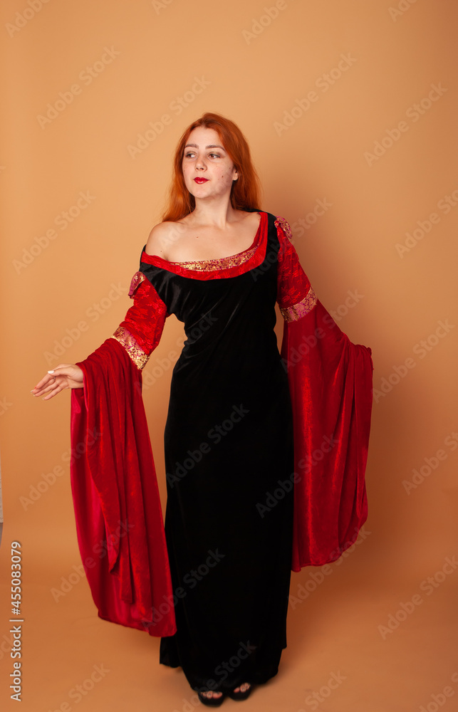 a girl in the image of a vampire countess witch on a holiday of evil spirits. charming red-haired witch on a beige background a girl in the image of a vampire countess witch on a holiday of evil spirits. charming red-haired witch on a beige background