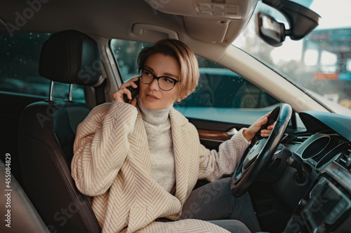 attractive stylish woman sitting in car dressed in coat