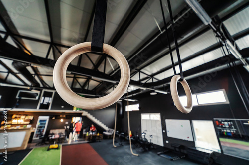 Focus on wooden sports hoops hanging from the wall in an urban modern indoor gym with no people. Sports equipment in various colors in a modern gym concept