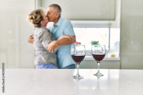 Senior caucasian couple kissing and dancing at the kitchen.
