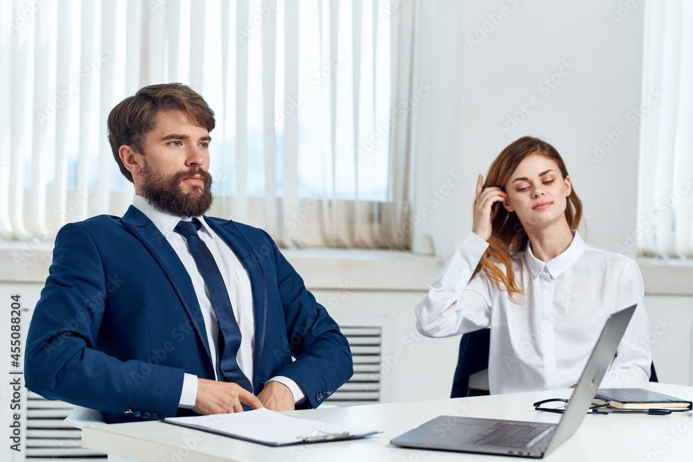 business man and woman talking at the table in front of laptop professionals technology