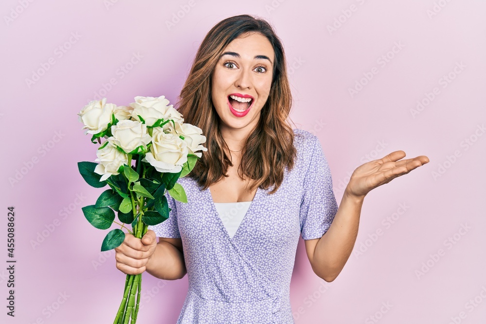 Young hispanic girl holding flowers celebrating achievement with happy smile and winner expression with raised hand Young hispanic girl holding flowers celebrating achievement with happy smile and winner expression with raised hand