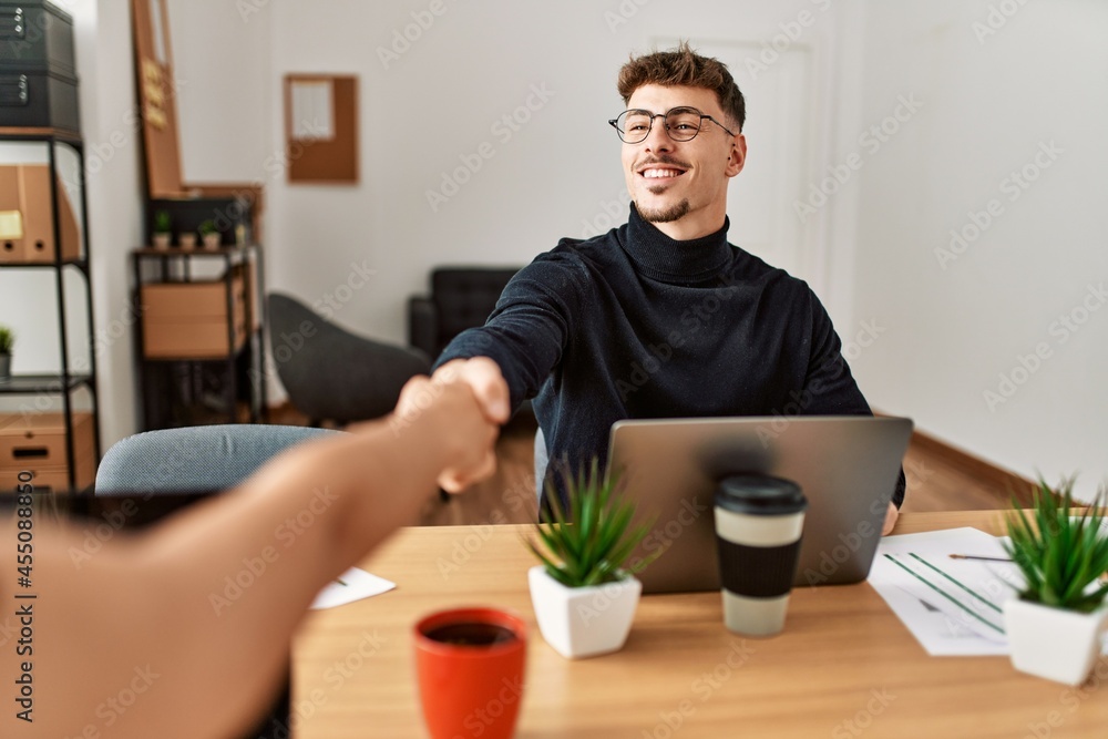 Two business workers smiling happy shaking hands at the office. Two business workers smiling happy shaking hands at the office.