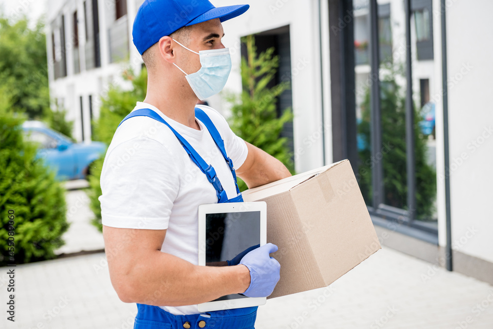 Young courier wearing a protective mask and gloves delivers goods during quarantine Young courier wearing a protective mask and gloves delivers goods during quarantine