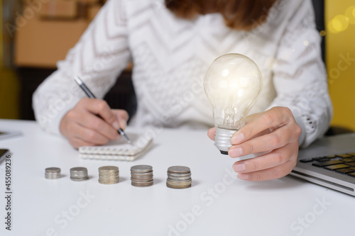 Money saving concept business man hand holding lightbulb with money stack. idea saving energy and accounting finance